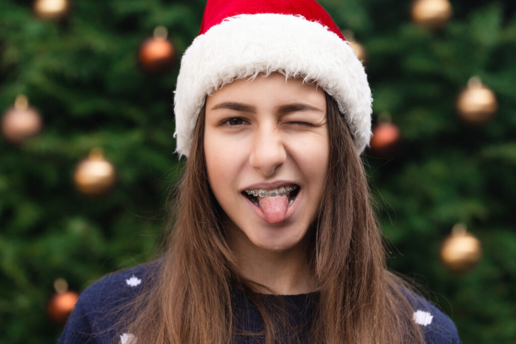close up portrait of young woman with braces wearing santa hat