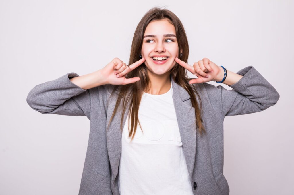 young woman smiling and pointing to her mouth